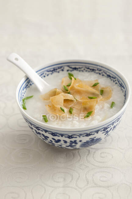 Gachas de desayuno tradicional chino con cuchara en un tazón - foto de stock
