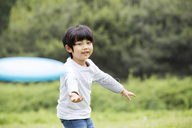 Feliz chico chino jugando frisbee - foto de stock