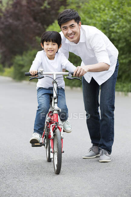 Père chinois enseignant fils à faire du vélo — Photo de stock