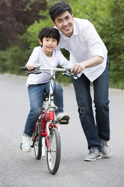 Китайський батько навчає сина їздити на велосипеді. — стокове фото