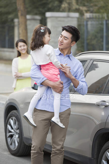 Feliz padre chino sosteniendo hija en sus brazos - foto de stock