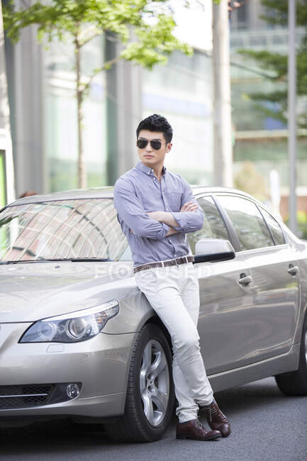 Молодий китаєць притискається до машини. — стокове фото