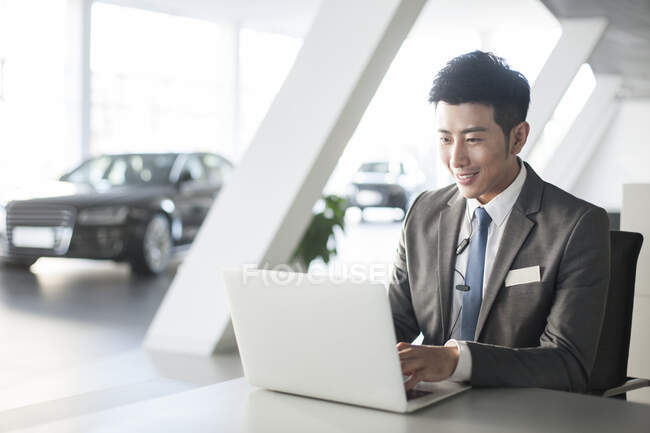 Joven empresario chino que trabaja con el ordenador portátil en la oficina - foto de stock