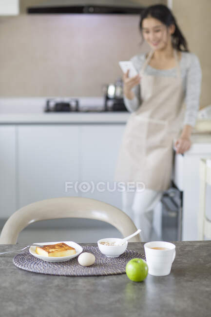 Young Chinese woman eating breakfast at home — Stock Photo