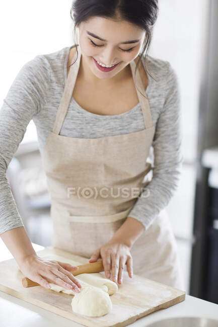 Красивая молодая женщина катит тесто на кухне — стоковое фото