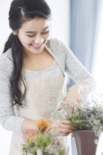 Young Chinese woman arranging flowers at home — Stock Photo