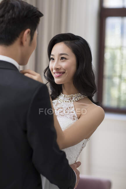 Jovem esposa chinesa ajustando laço para o marido — Fotografia de Stock