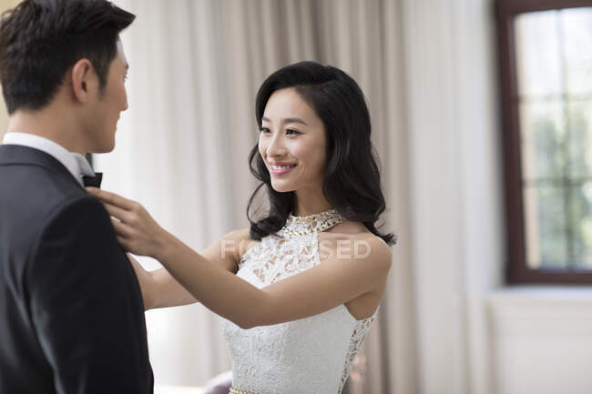 Young Chinese wife adjusting bow tie for her husband — Stock Photo