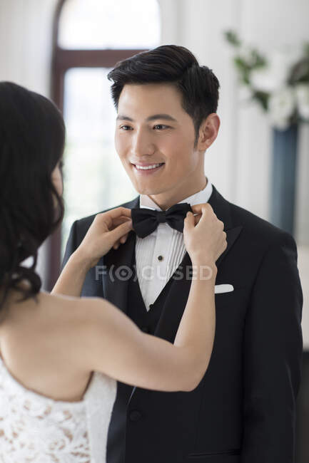 Young Chinese wife adjusting bow tie for her husband — Stock Photo
