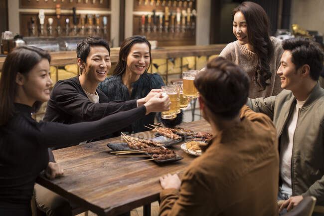 Felice amici cinesi brindare e parlare nel bar — Foto stock