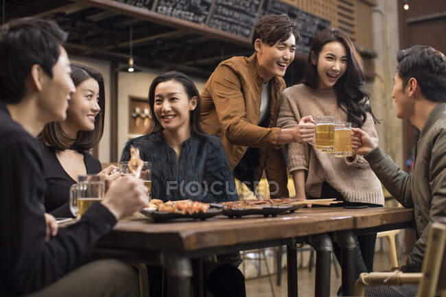 Glückliche chinesische Freunde trinken Bier und unterhalten sich in der Bar — Stockfoto
