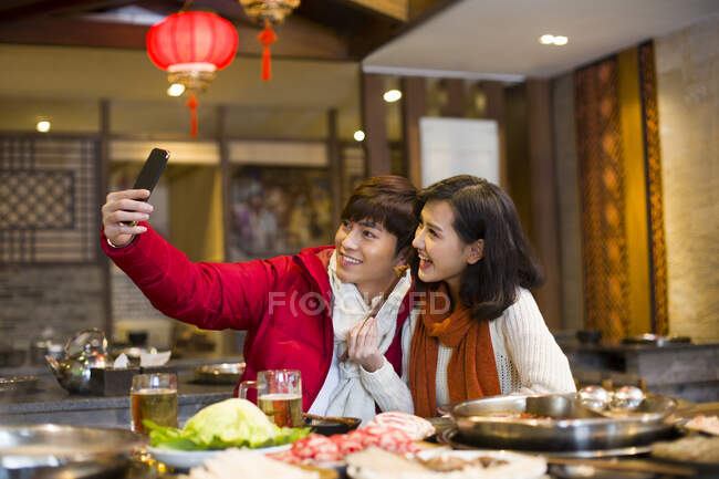 Jeune couple chinois prenant autoportrait avec un téléphone intelligent — Photo de stock