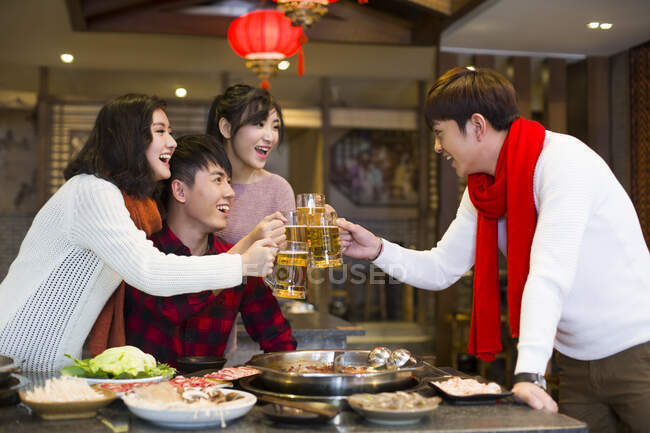 Молоді китайські друзі п'ють пиво в ресторані 