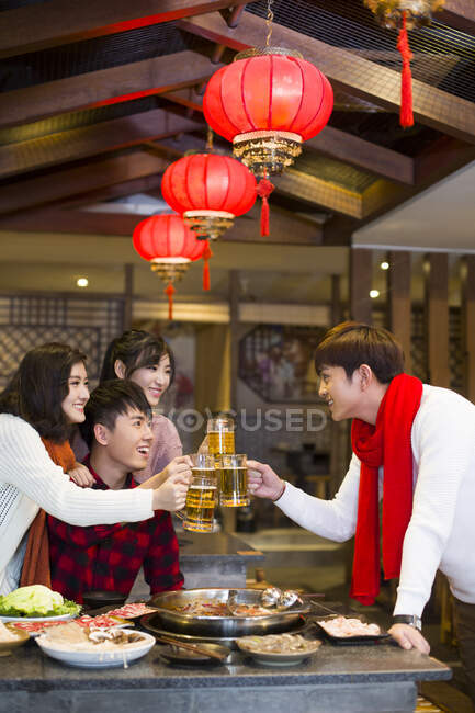 Молодые китайские друзья пьют пиво в ресторане с горячим баром — стоковое фото