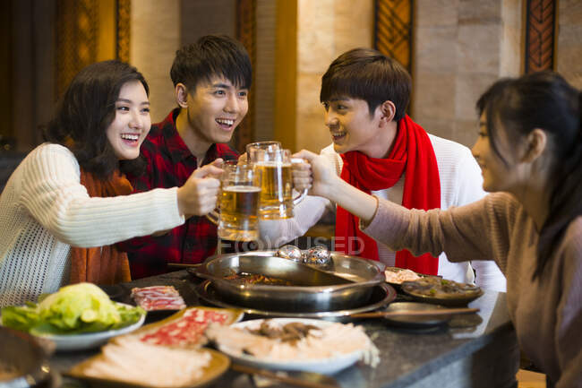 Молодые китайские друзья пьют пиво в ресторане с горячим баром — стоковое фото