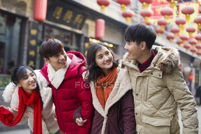 Молодые китайские друзья идут вместе по улице — стоковое фото