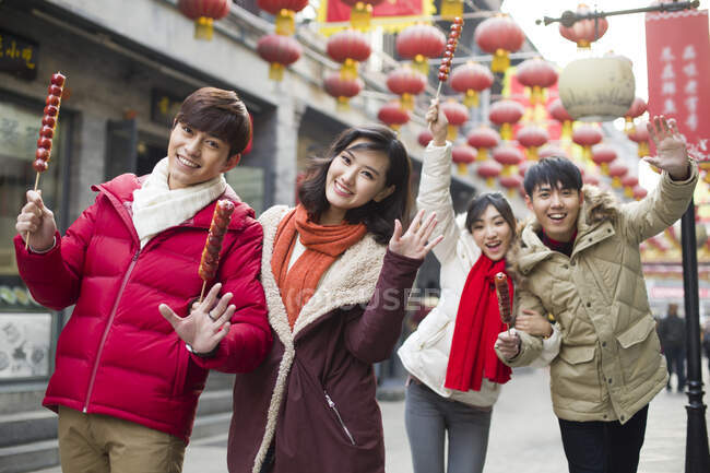Jóvenes amigos chinos con bayas de haw confitadas celebrando el Año Nuevo Chino - foto de stock