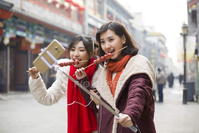 Jóvenes mujeres chinas tomando autorretrato con un teléfono inteligente - foto de stock