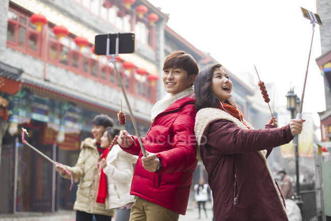 Jeune couple chinois prenant autoportrait avec les téléphones intelligents — Photo de stock