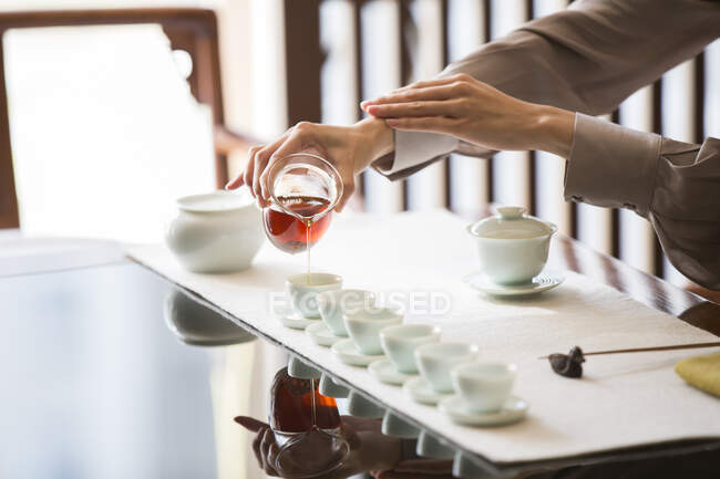 Обрезанный снимок женщины, проводящей чайную церемонию, наливающей чай — стоковое фото