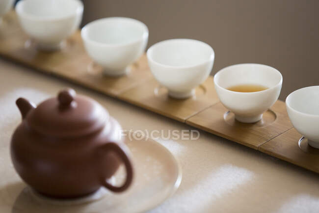 Chinese tea pot and tea cups in row — Stock Photo