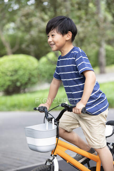 Happy little Chinese boy riding bike in park — Stock Photo