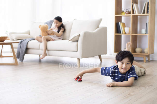 Happy Chinese sibling playing with toys in living room — Stock Photo