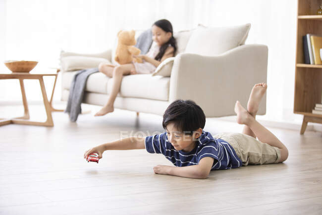 Glückliche chinesische Geschwister spielen mit Spielzeug im Wohnzimmer — Stockfoto