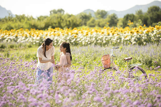 Chinese mother and daughter in flower field — Stock Photo