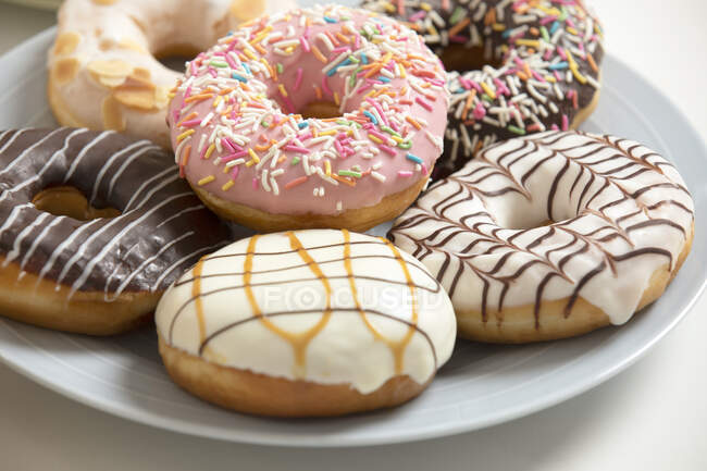 Köstliche Donuts auf Teller mit verschiedenen Glasuren und Streusel — Stockfoto