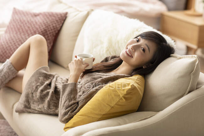 Giovane donna che beve caffè a casa — Foto stock