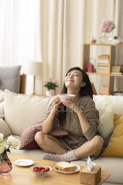 Young Chinese woman having breakfast at home — Stock Photo