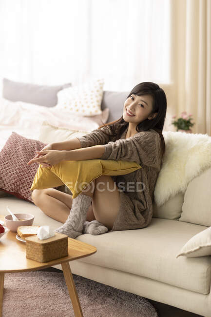 Jeune femme chinoise assise sur le canapé — Photo de stock
