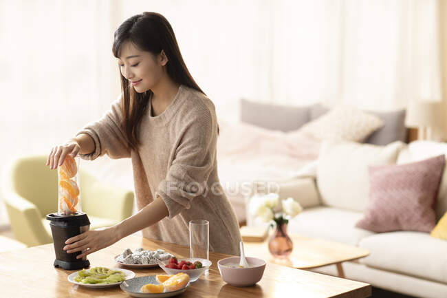 Молода китайка готує сік удома. — стокове фото