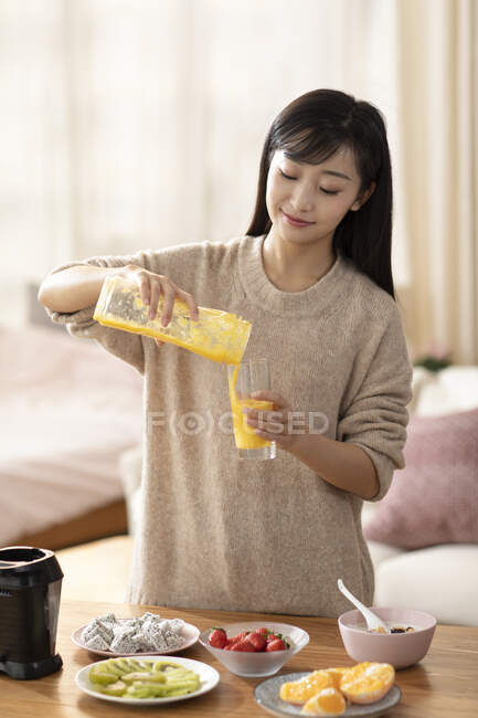 Молодая китаянка со свежим апельсиновым соком — стоковое фото