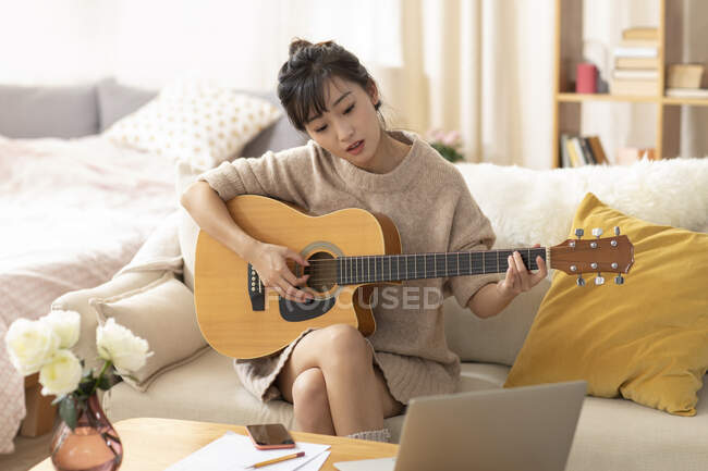 Жінка вчиться грати на гітарі вдома — стокове фото