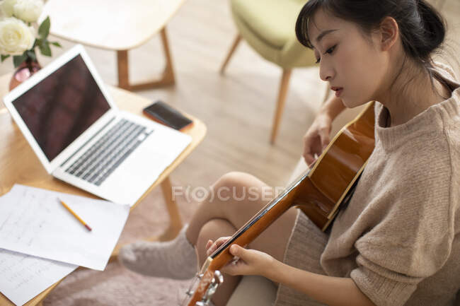 Mujer aprendiendo a tocar la guitarra en casa - foto de stock