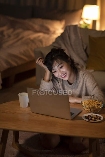 Joven mujer china viendo la película en el ordenador portátil - foto de stock