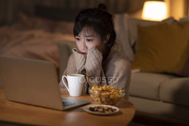 Молода китайка дивиться фільм на ноутбуці. — стокове фото