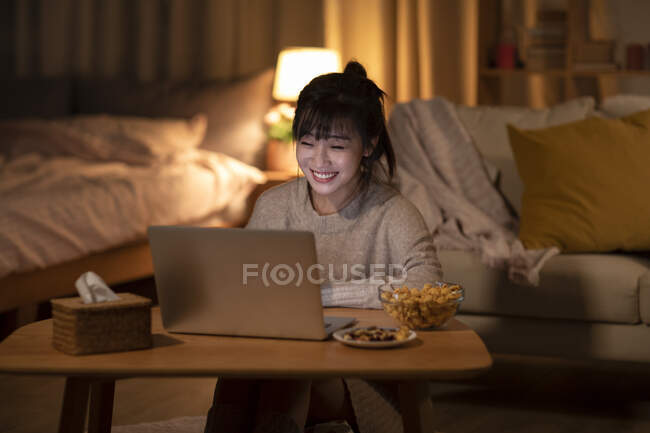 Mulher assistindo filme no laptop sentado no chão por sofá — Fotografia de Stock