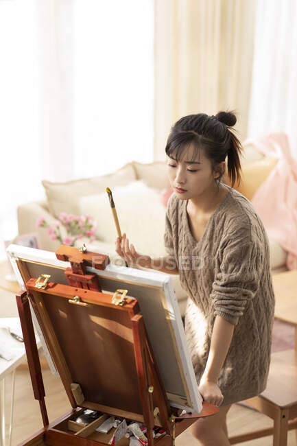 Young Chinese woman painting at home — Stock Photo