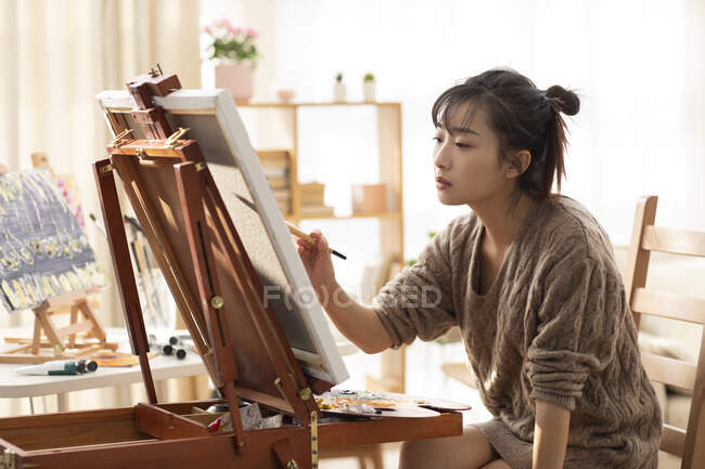 Young chinese woman painting at home — Stock Photo