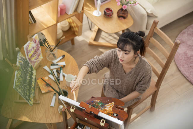 Jeune femme chinoise peinture à la maison — Photo de stock