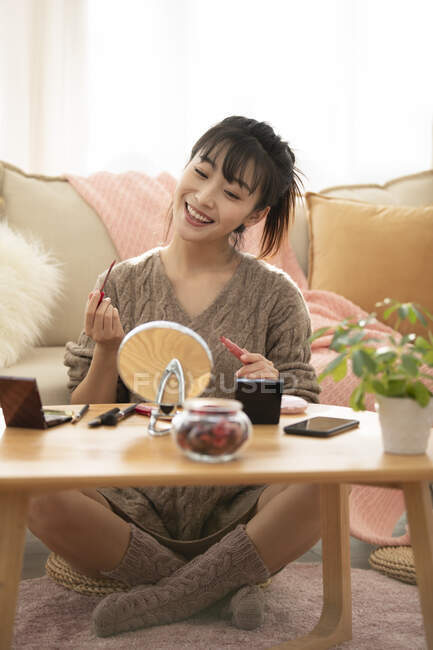 Young Chinese woman applying makeup at home — Stock Photo