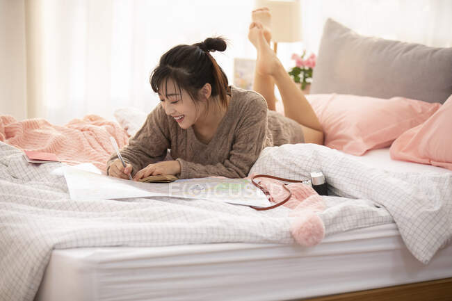Joven mujer china haciendo plan de viaje en casa - foto de stock