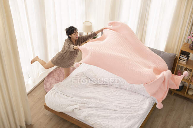 Jovem chinesa fazendo cama em casa — Fotografia de Stock