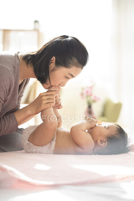 Junge chinesische Mutter küsst Babys Füße — Stockfoto