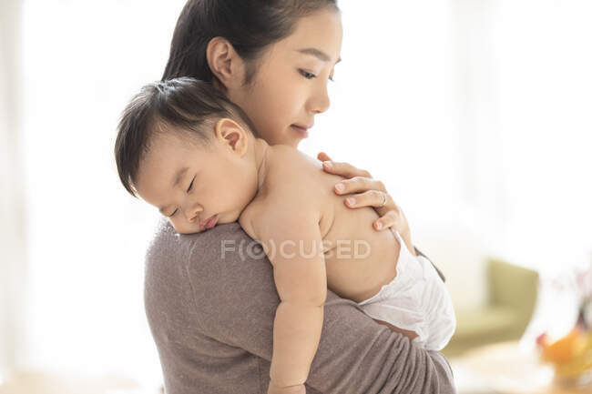 Jovem chinesa mãe segurando seu bebê dormindo — Fotografia de Stock