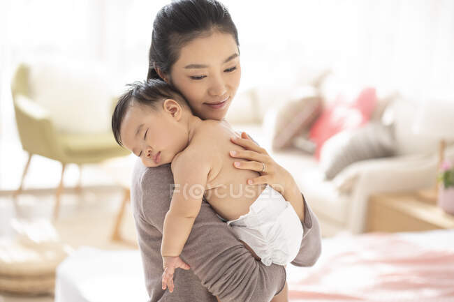 Молодая китайская мама держит спящего ребенка — стоковое фото
