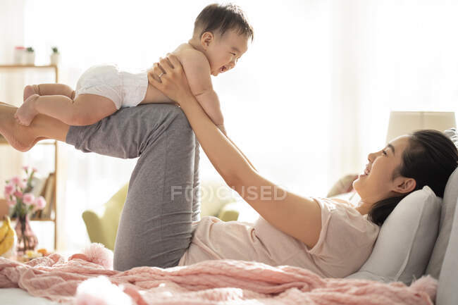 Mother and baby playing and laughing on couch — Stock Photo